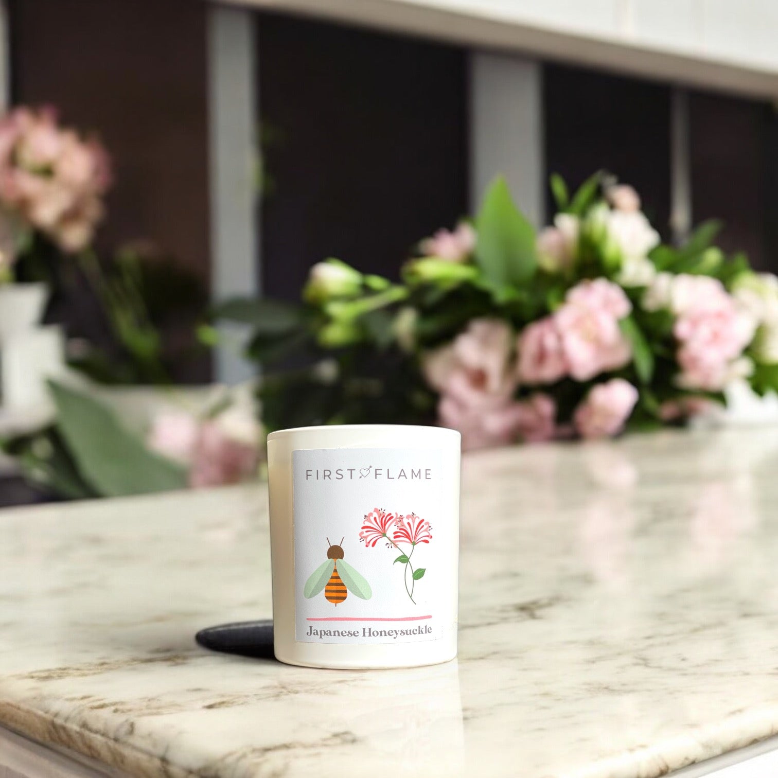 Japanese Honeysuckle candle styled on marble bench with pink flowers